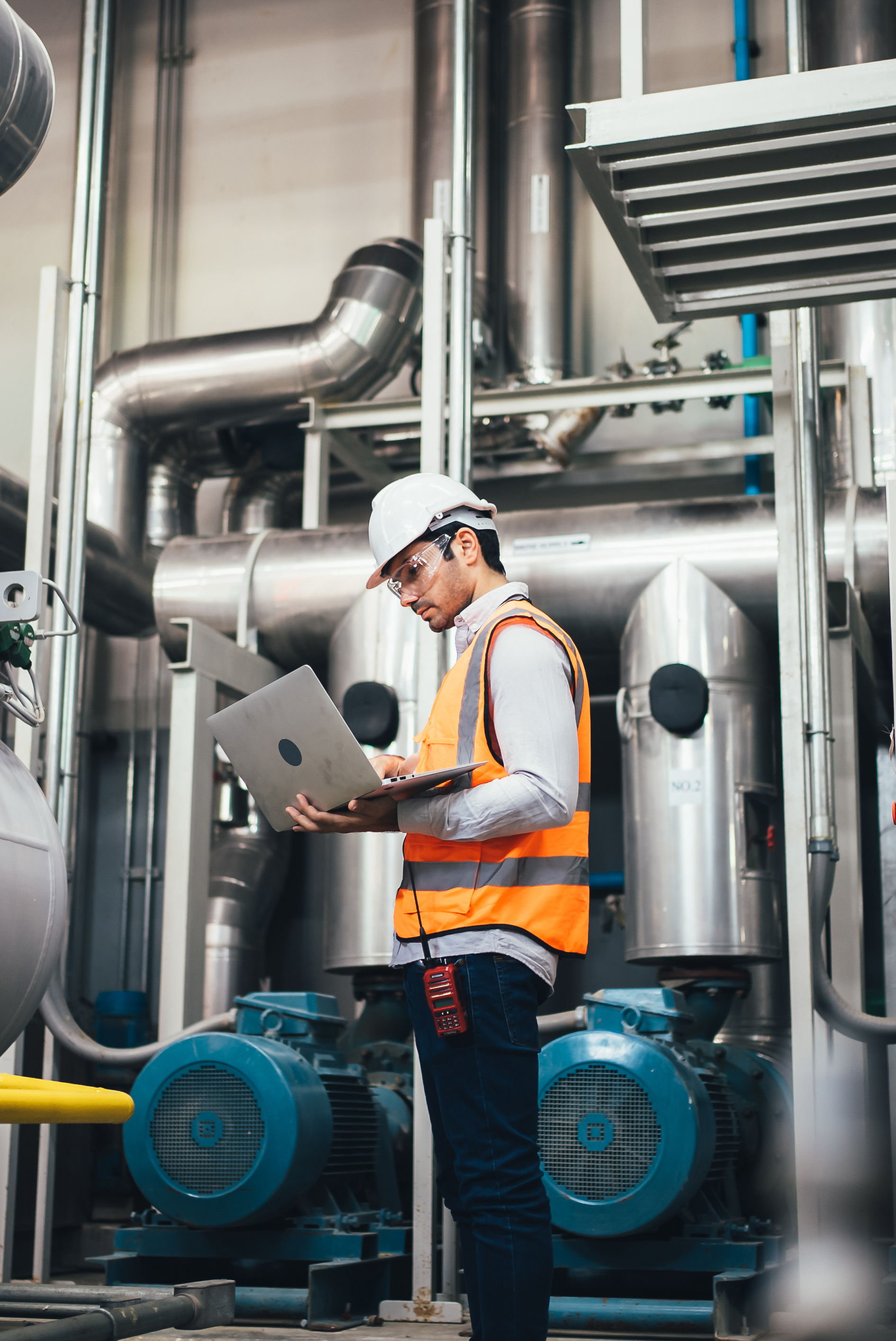 Professional worker of modern factory using laptop controlling program to automatic machinery. Engineering with laptop Programmable Logic Controller to manage large machine working full automatic.