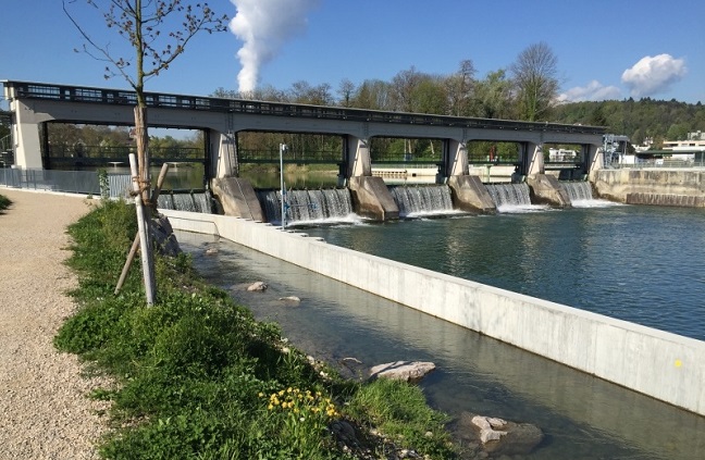 An der Aare. Das ist ein Teil der Kraftwerks Rüchlig in Aarau, das Axpo bis im Sommer 2015 in dreienhalb Jahren Bauzeit für 120 Mio Franken komplett erneuert hat. Die neue Anlage erfüllt höchste Umweltstandards und zeichnet sich durch einen verbesserten Hochwasserschutz sowie eine um rund 25% gesteigerte Energieproduktion aus.